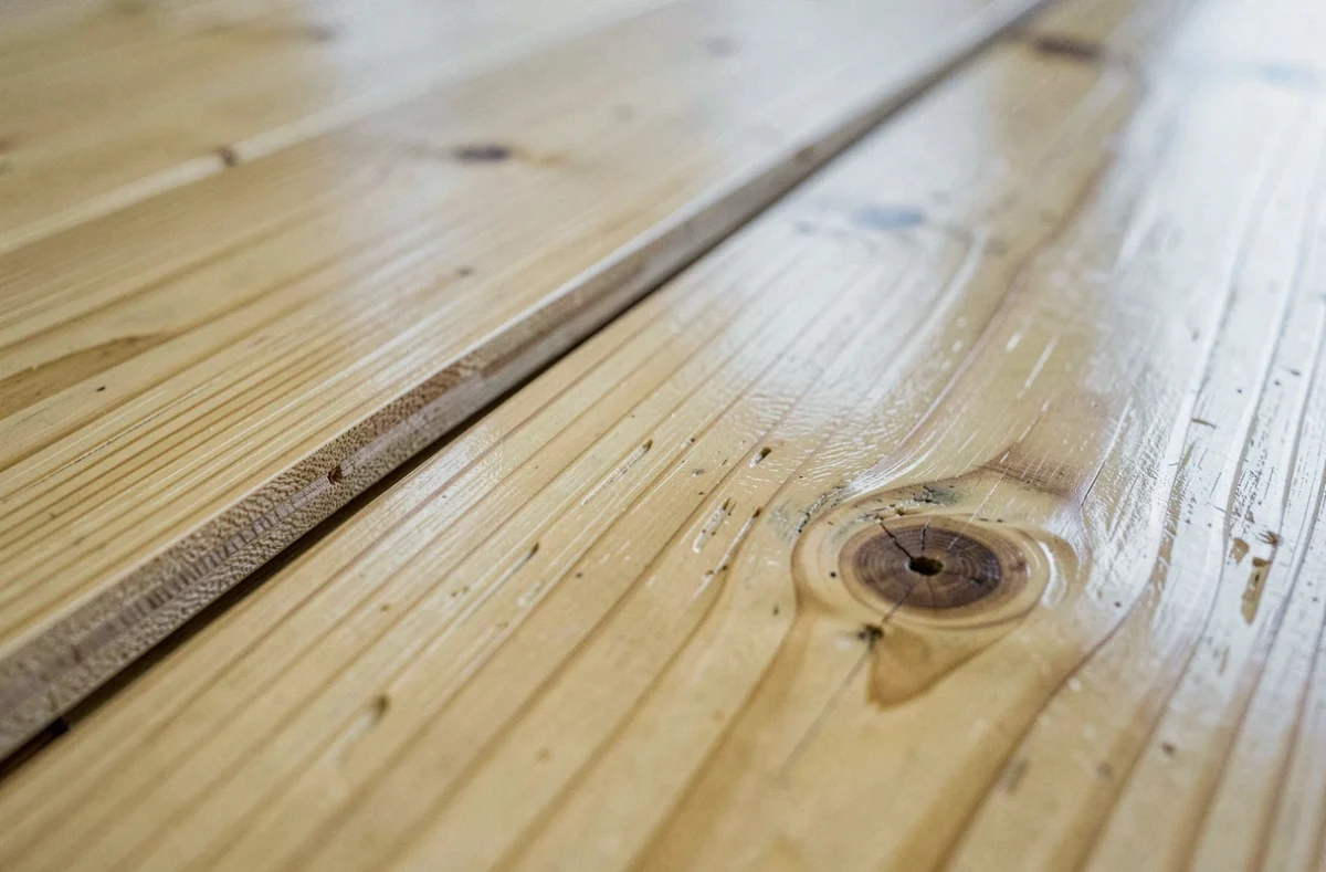 Détail macro d'un parquet en pin massif avec comparaison finition satinée et bois brut